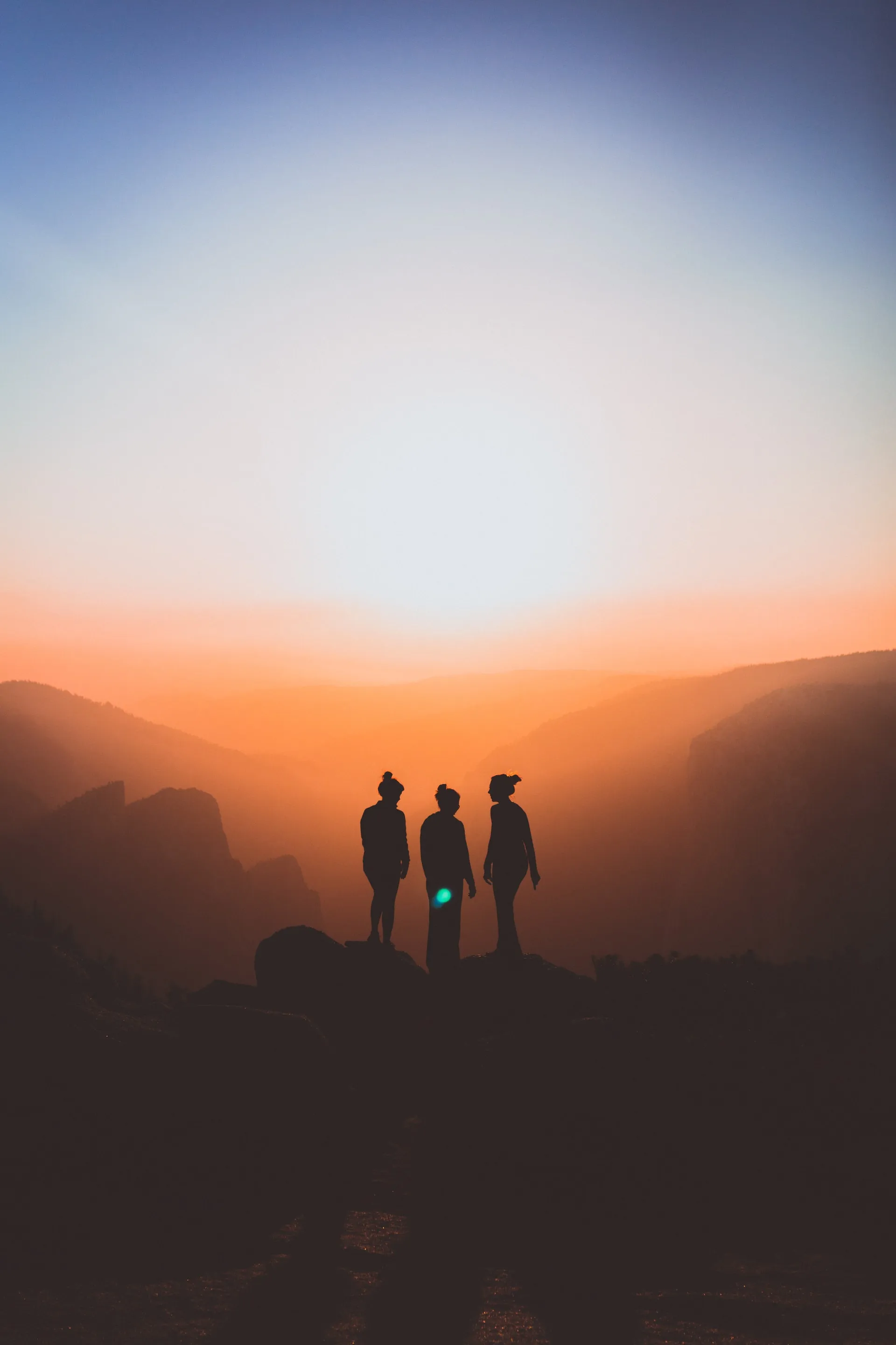 3 People looking at the sun on a mountain